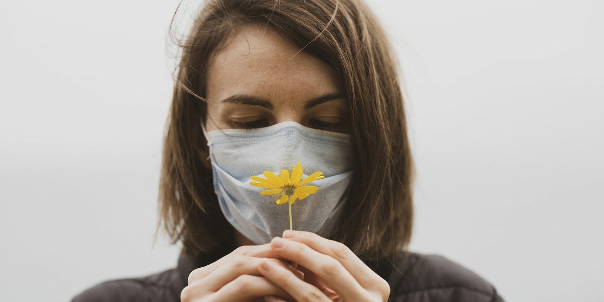 femme masquée tenant une fleur