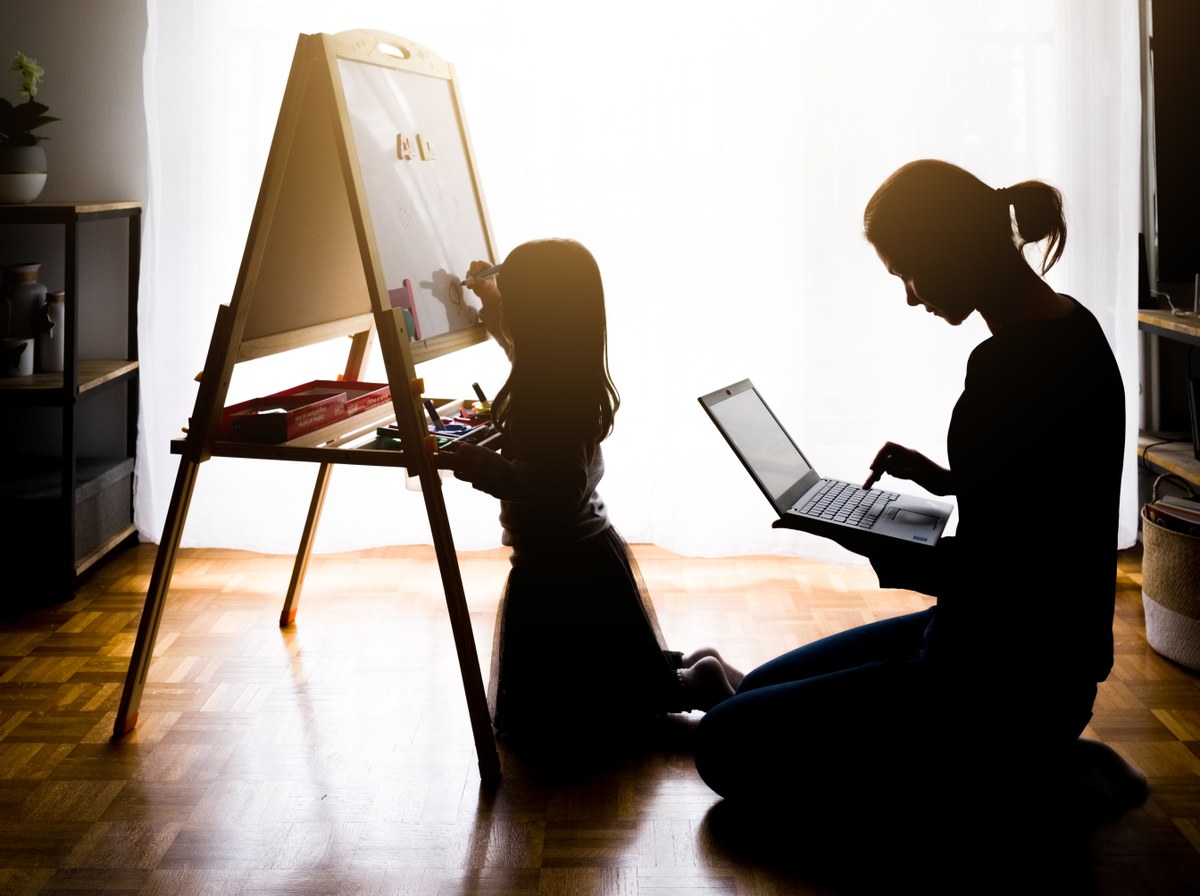 femme travaillant et surveillant sa fille qui dessine